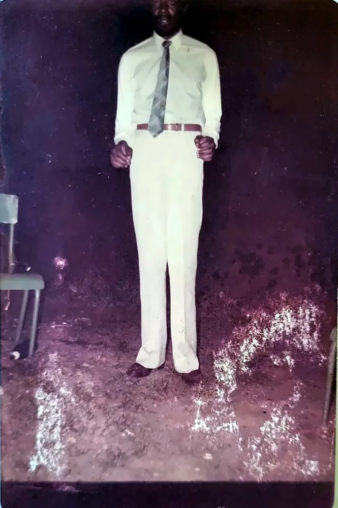 Paul Sanjong debout, chemise blanche et cravate