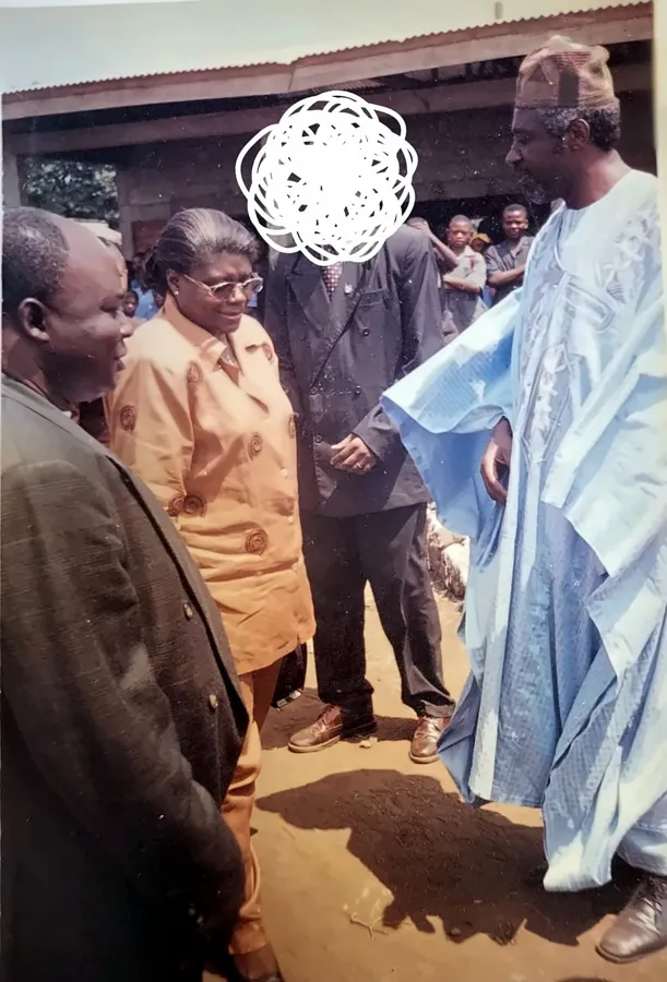 Paul Sanjong en grand boubou bleu, saluant des invités